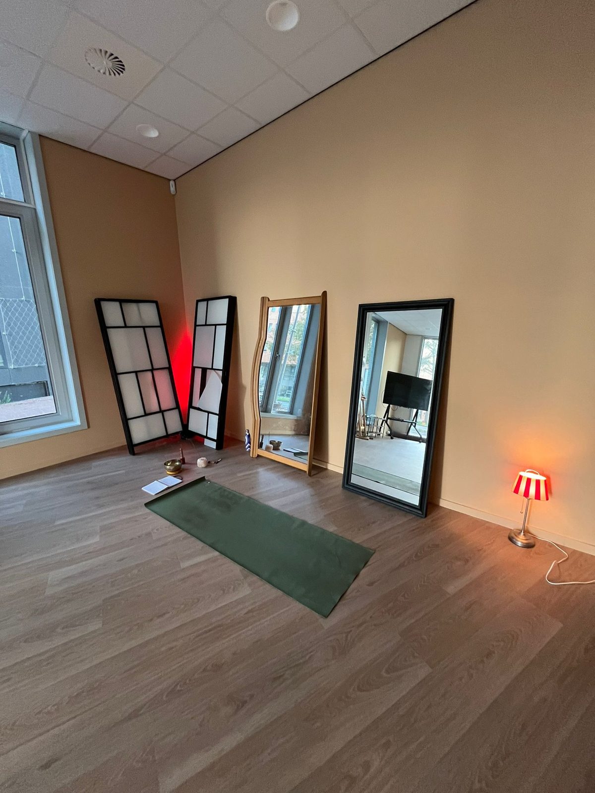 De nieuwe ruimte in opbouw, met spiegels en een yogamat