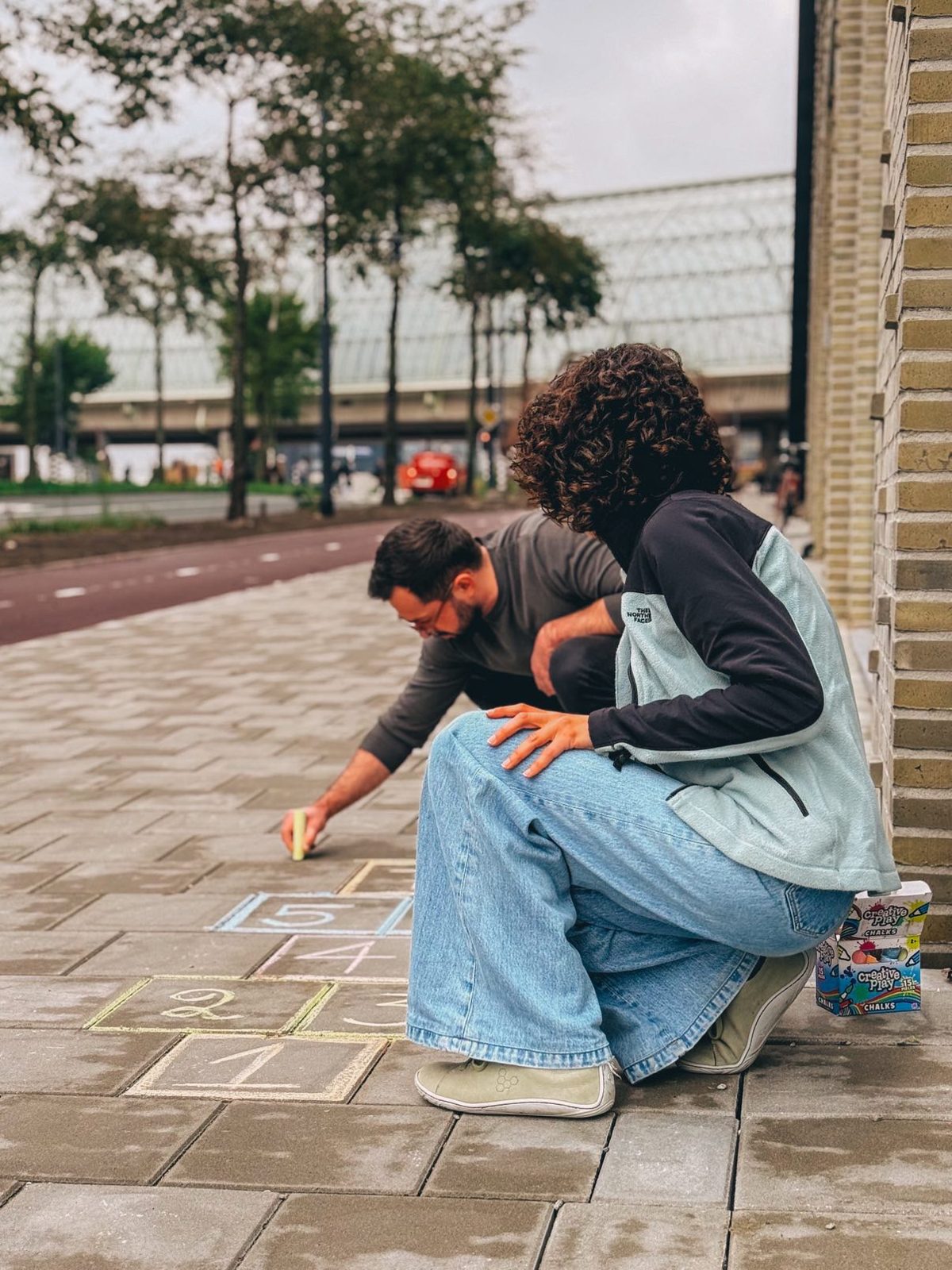 Buurtbewoners maken stoepkrijttekeningen voor de deur van de buurtkamer